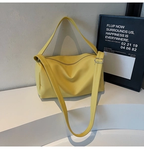 Detail view of large yellow pebble leather crossbody bag with adjustable wide strap