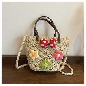 Detail of woven straw bucket bag with red polka dot bow and colorful knit floral accents