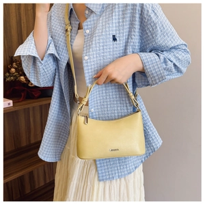 Detail of yellow vintage leather baguette bag with metal logo and detachable strap