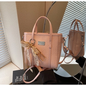Dettaglio della borsa a secchiello rosa intrecciata con fiocco in pizzo e logo