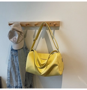 Detail view of bright yellow pebbled leather shoulder bag hanging on a wooden hook