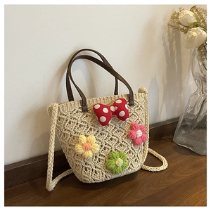 Detailed close-up of woven straw bucket bag with floral crochet and polka dot bow