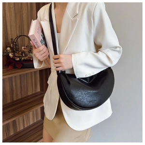 Close-up of black leather crescent crossbody bag with minimalist strap on a model