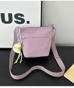 Dettaglio borsa a tracolla in nylon lavanda con ciondolo a forma di luna gialla