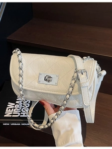 White quilted mini crossbody bag with silver chain strap and metal turn-lock closure