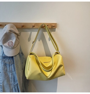Detail of large bright yellow pebbled leather tote bag hanging on wooden coat rack