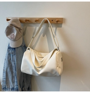 Close-up of cream white textured leather crossbody bag hanging on a wooden hook