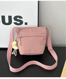 Dettaglio della borsa a secchiello in nylon rosa con ricamo e ciondolo a luna morbida