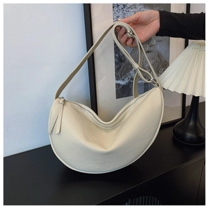 Detail of minimalist beige crescent bag with adjustable strap and textured leather