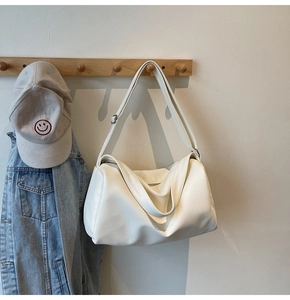 Detailed view of a white pebble-grain tote bag hanging on a wooden hook in a cozy setting