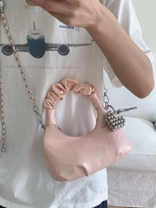 Pink pleated cloud bag with elegant silver chain strap and heart charm on mannequin