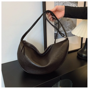 Detail of dark brown crescent bag showing the glossy vintage leather texture and zipper