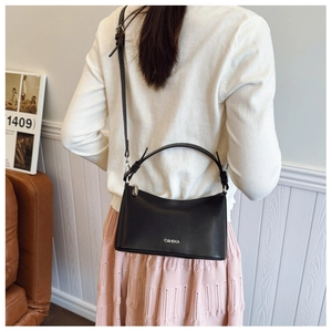 Model view of black leather shoulder bag with C&HEKA logo and round handle detail