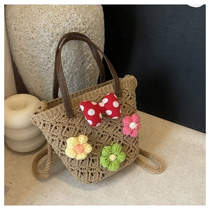 Close-up of handmade woven straw bag with crochet floral accents and a red polka dot bow