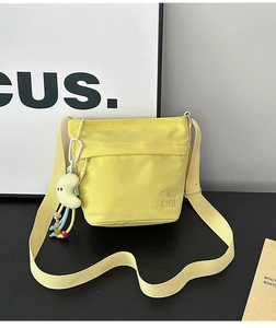 Dettaglio della borsa tote in nylon giallo con ricamo OMQ CNH e ciondolo a luna