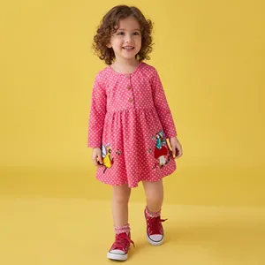 Detail of pink polka dot girls' dress featuring intricate cartoon embroidery and buttons