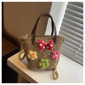Detail of woven beach bucket bag featuring crochet flower charms and a red bow accent