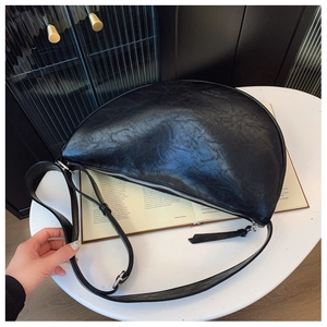 Detail shot of black leather crescent bag with smooth zipper and adjustable strap