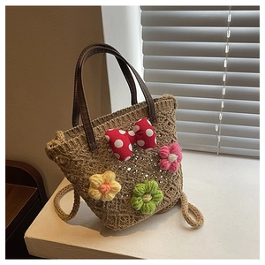 Detailed close-up of woven straw bucket bag with floral crochet and red polka dot bow decoration