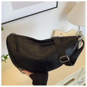 Detail shot of the black crescent saddle bag with textured leather and silver zipper
