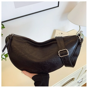 Detail showing the matte texture and brand embossing on a black crescent shoulder bag