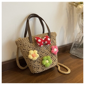 Detail of woven straw bucket bag with floral crochet charms and polka dot bow