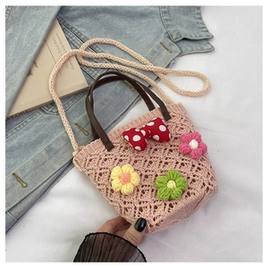 Detail of pink crochet bucket bag featuring 3D knit flowers and a red polka dot bow