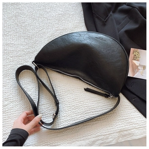 Detail of black pebbled leather half-moon bag with adjustable strap and metal zipper