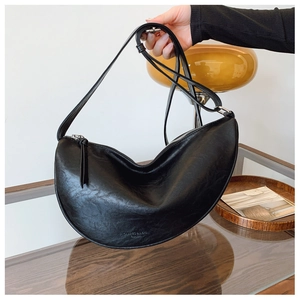 Detail of black matte faux leather crossbody crescent bag with adjustable shoulder strap