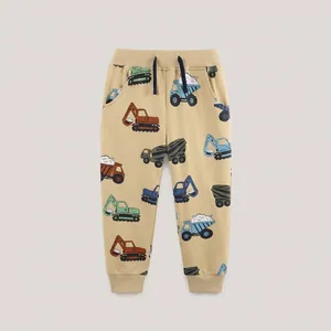 Detail of kids beige joggers featuring cartoon construction vehicle prints and black drawstring