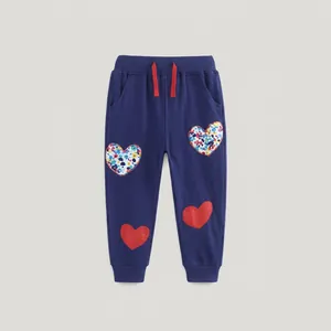 Detail view of navy blue kids joggers with red drawstring and heart-shaped floral patches