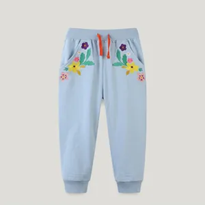 Detail view of light blue cotton joggers with floral embroidery and orange drawstring tie