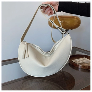 Detail shot of the lychee texture and silver metal zipper on the beige crescent bag