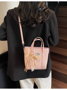 Secchiello rosa intrecciato con fiocco in pizzo indossato da modella in tailleur nero