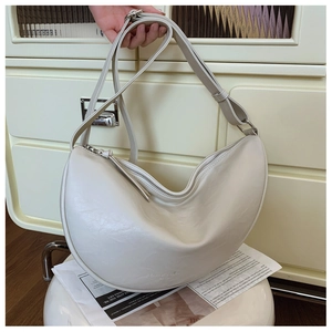 Detail of soft cream crescent bag featuring smooth leather texture and adjustable strap