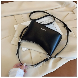 Detail of black leather crescent bag with silver logo and adjustable strap on a blazer