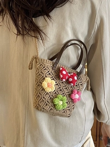 Handmade hollow straw bucket bag with floral accents and brown leather handle
