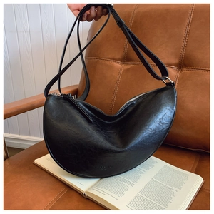 Detail of black faux leather crescent bag with litchi grain texture and silver zipper