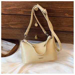 Close-up of a cream leather crescent bag with silver C&HEKA logo on a vintage wooden desk