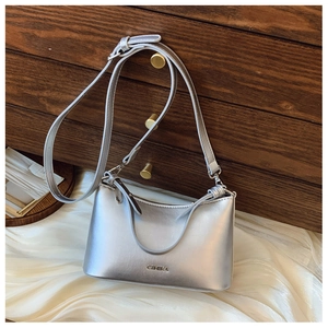 Detail of silver metallic tote bag with logo on white silk fabric and wooden cabinet