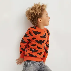 Détail d'un sweat orange pour garçon avec des chauves-souris noires et un jean gris