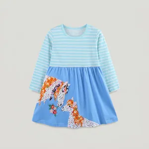 Détail des motifs de poney de dessin animé brodés sur la robe bleue à manches longues