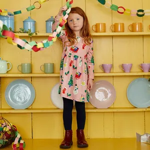Détail d'une robe rose pour fille avec motifs de Noël, Père Noël et sapins