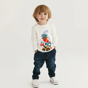 Détail d'un sweat blanc pour enfant avec imprimé pelleteuse et pantalon en jean bleu