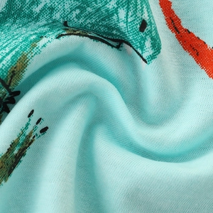 Close-up of light blue cotton boy's t-shirt with colorful cartoon dinosaur print