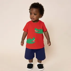 Dettaglio maglietta rossa per bambini con stampa coccodrillo e pantaloncini blu navy