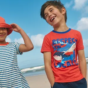 Dettaglio maglietta rossa in cotone da bambino con balena e completo estivo a righe
