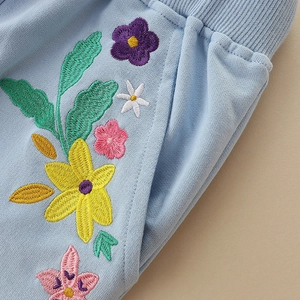 Pantalón deportivo azul claro para niña con bordado floral en el bolsillo lateral