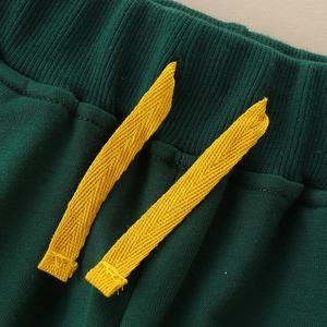 Close-up of kids dark green joggers with elastic ribbed waist and bright yellow drawstrings