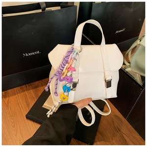 Detail of white PU leather mini backpack with metal buckles and colorful letter pendant